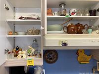 Shelf view showing teapots, plastic bowl, glassware and decor