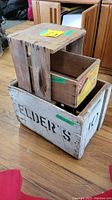 Three wooden crates stacked, showing Elder's white painted crate at the bottom, Sun Mandarin Oranges crate on top inside a larger crate.
