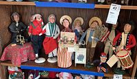 Shelf display of nine Byers Choice Caroler figurines and small Uncle Sam
