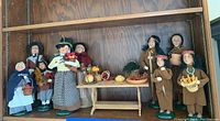Wide shot of wooden shelf with Byers’ Choice Thanksgiving caroler figurines and harvest table display