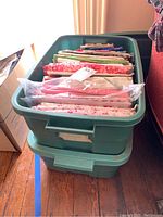 Two stacked green plastic tubs filled with folded fabric and fabric kits