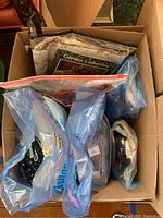 View inside a box containing multiple ziplock bags with fabric pieces and quilt patterns.