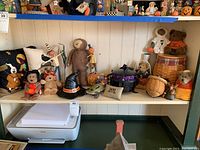 Wide shelf view showing assortment of Halloween decor, figurines, pillows, baskets, and Boyds Bears on two shelves.
