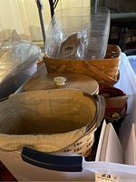 View of various Longaberger baskets including one with a washed linen liner and lid, plastic containers in the background.