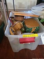 Clear plastic bin containing multiple Longaberger baskets of various sizes with fabrics and lids