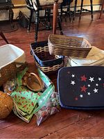 Various Longaberger baskets and insulated tote inserts arranged on wooden floor with green fabric and small basket knobs.