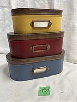 Three metal nesting tins stacked showing yellow, red and blue with brown lids and metal label holders, excellent condition.