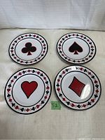 Set of four 9-inch melamine plates with card suit designs (club, spade, heart, diamond) arranged on a fabric surface.