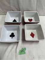 Top view of four square ceramic poker dishes showing interior card suit symbols: spade, heart, club, diamond.