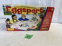 Photograph of the front of the Eggspert game box showing children playing the game with colorful egg-shaped buttons.
