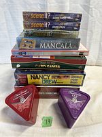 Stack of factory sealed board games including two Scene It? game packs, Mancala wood game, Fun with Architecture card game, card games boxed set, Nancy Drew Mystery Party Game with box damage, and two triangular Trivial Pursuit singles sets.