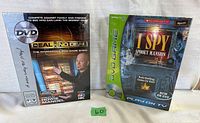 Front view of two factory sealed DVD board games: Deal or No Deal and Scholastic I Spy Spooky Mansion