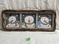 Full view of the wooden framed wall sign showing three snowman illustrations labeled Live, Love, Laugh.