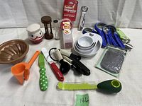 Overview photo showing various kitchen gadgets including measuring cups, peelers, timers, can opener, and funnel.