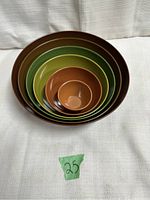 Top-down view of the set of five nesting bowls showing the color gradation from dark brown to green tones with the smallest bowl in the center.