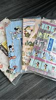 Close-up view of the four unopened discrete vintage Disney gift wrap packages, highlighting character motifs and package condition.