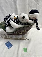 Metal sleigh with plush polar bear and two snowmen inside, front view showing tag on sleigh.