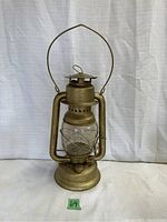 Full front view of the vintage metal beacon lantern illustrating the metal body, handle, and glass globe intact.