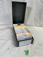 Front angled view of the open vintage gray metal recipe box showing rows of colorful index cards organized with alphabetical dividers and labeled sets.