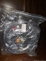 Coiled 150 feet black security camera cord inside transparent plastic bag with visible red and yellow RCA connectors.