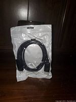 Full view of the HDMI to DisplayPort adapter cable in sealed packaging, showing the cable and connectors coiled inside the plastic bag.