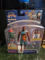 Front view of the Space Jam LeBron James action figure packaged with Acme rocket pack and small rocket accessory, showing figure attire and packaging details.