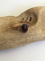 Front angle of the gold ring showing oval purple cabochon set in bezel setting on yellow gold band.