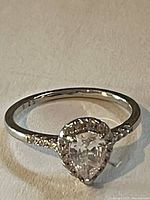 Close-up photo of the 925 sterling silver ring with pear-shaped clear stone and side accent stones, showing the band and stone details.