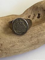 Front view of the vintage sterling silver signet ring showing the detailed crest engraving on the round face and tarnished surface.