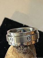 Close-up photo of silver tone spinner ring placed on a textured object to highlight the design and condition.