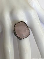 Close-up front view of antique sterling silver ring with rose quartz center stone on white hand display.