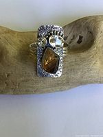 Front view of the sterling silver ring showing rectangular textured face with two gemstones set.