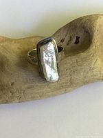 View of ring top showing elongated irregular pearl set in sterling silver bezel with smooth band