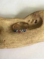 Front view of the 10K gold ring showing red, clear, and blue crystals set in a row on the band.