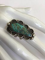 Close-up of the top front turquoise stone and silver scalloped bezel setting showing patina and tarnish.