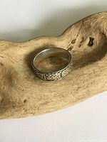 Front and top view of the vintage sterling silver Celtic design ring showing detailed knot pattern and signs of tarnish on a wooden surface.
