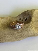Front view of vintage sterling silver ring with rose gold tone and central clear solitaire stone, set on a wooden background.