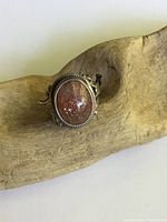 Ring displayed on a piece of raw wood highlighting the opal stone and silver setting.