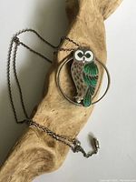 Owl pendant necklace draped over a wood background showing pendant details and chain length