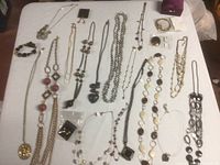 Top-down view of assorted costume jewelry including necklaces and bracelets laid out on a white surface.