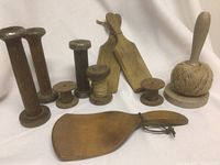 Overview of lot showing 3 large wooden spools with metal tops, 3 small wooden spools including one wrapped with twine, wooden paddles, and wooden twine holder with twine ball.
