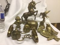 Overview of entire lot showing all brass items including candlestick holders, horse, dog, birds, tray, and pig coin bank