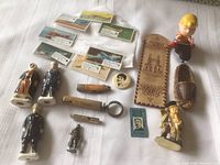 All items arranged on white surface including figurines, wooden souvenirs, matchbook covers, and small vintage collectibles