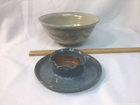 Photo of large light beige ceramic bowl and smaller bluish-green dip dish with scalloped center, placed on a white cloth with a ruler for scale.