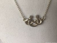 Close-up of horseshoe pendant on necklace showing polished silver and shape.
