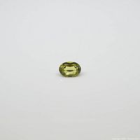 Clear photo showcasing the oval, faceted yellow-green tourmaline gemstone against a white background.