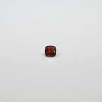 Front diagonal view of the square cushion red spinel gemstone showing its faceting and deep red color on white background.