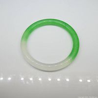 Top-down photo of the round jade bangle showing white to green gradient color, polished surface