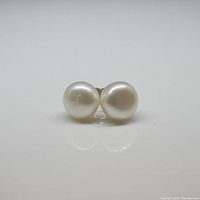 Front view of both round white pearls placed side by side on a white background