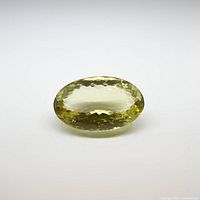 Oval lemon citrine gemstone shown from a top flat view on a white background, showcasing its color and facets.